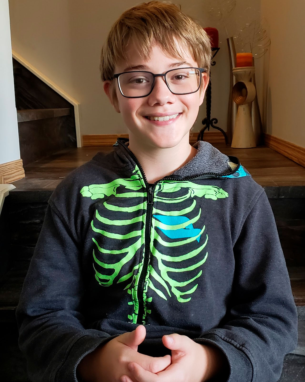 A photo of Gabriel sitting on a set of stairs looking into the camera and smiling.